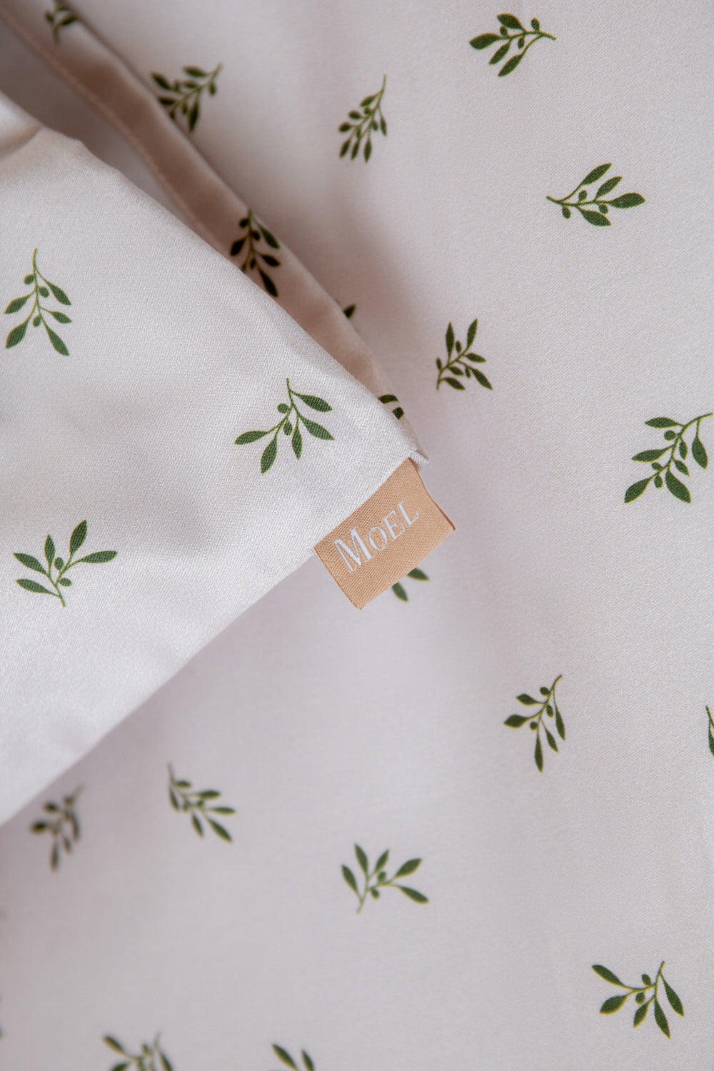 Fabric with green olive pattern and a visible brand label on a light background moel