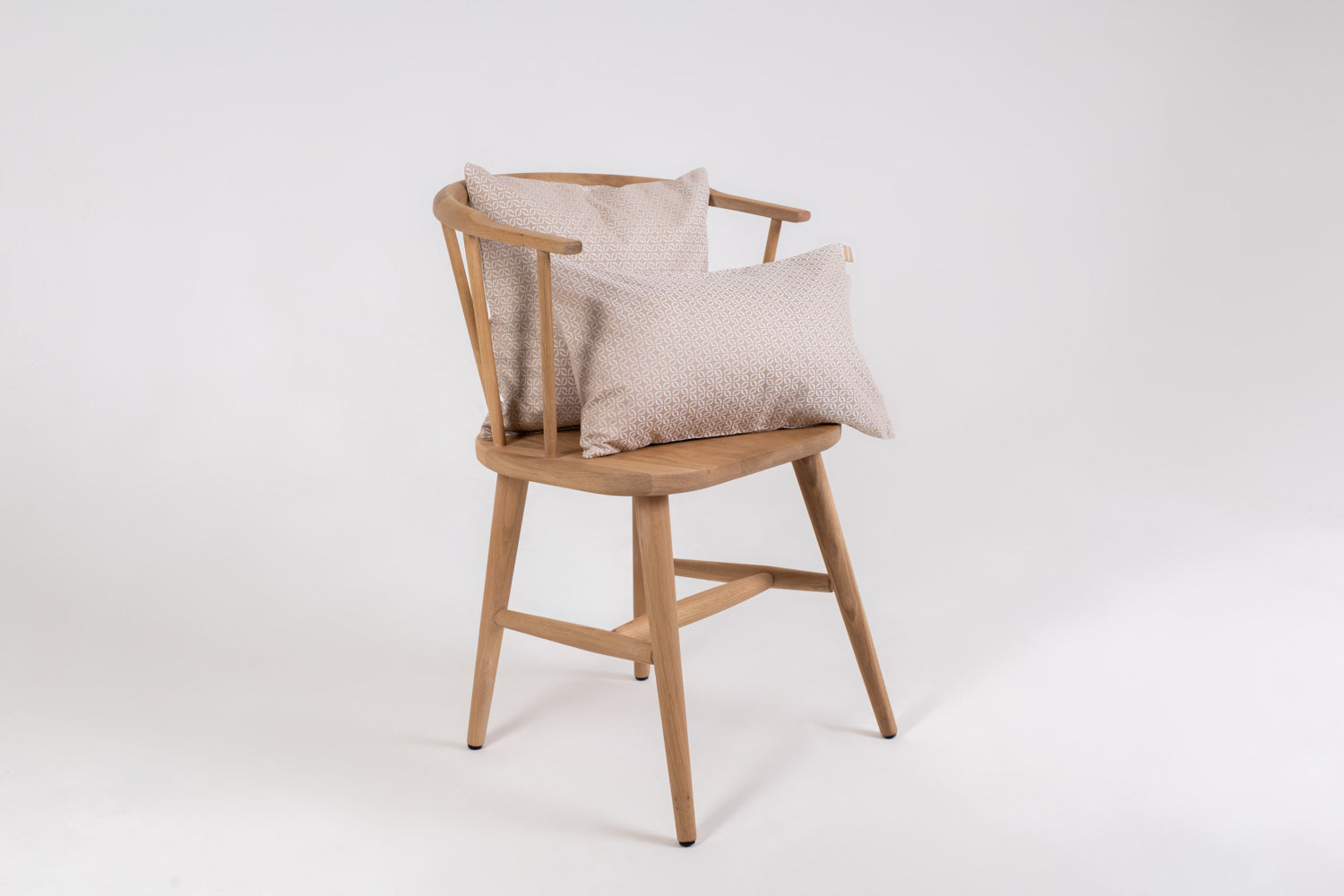 A beige cushion with a clover pattern on a wooden chair with no one sitting