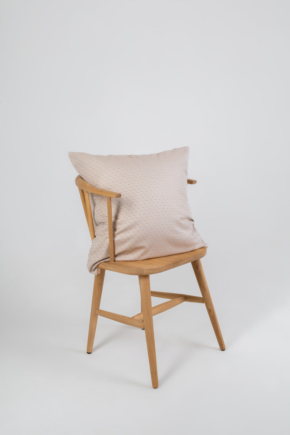 A beige cushion with a clover pattern on a wooden chair with no one sitting