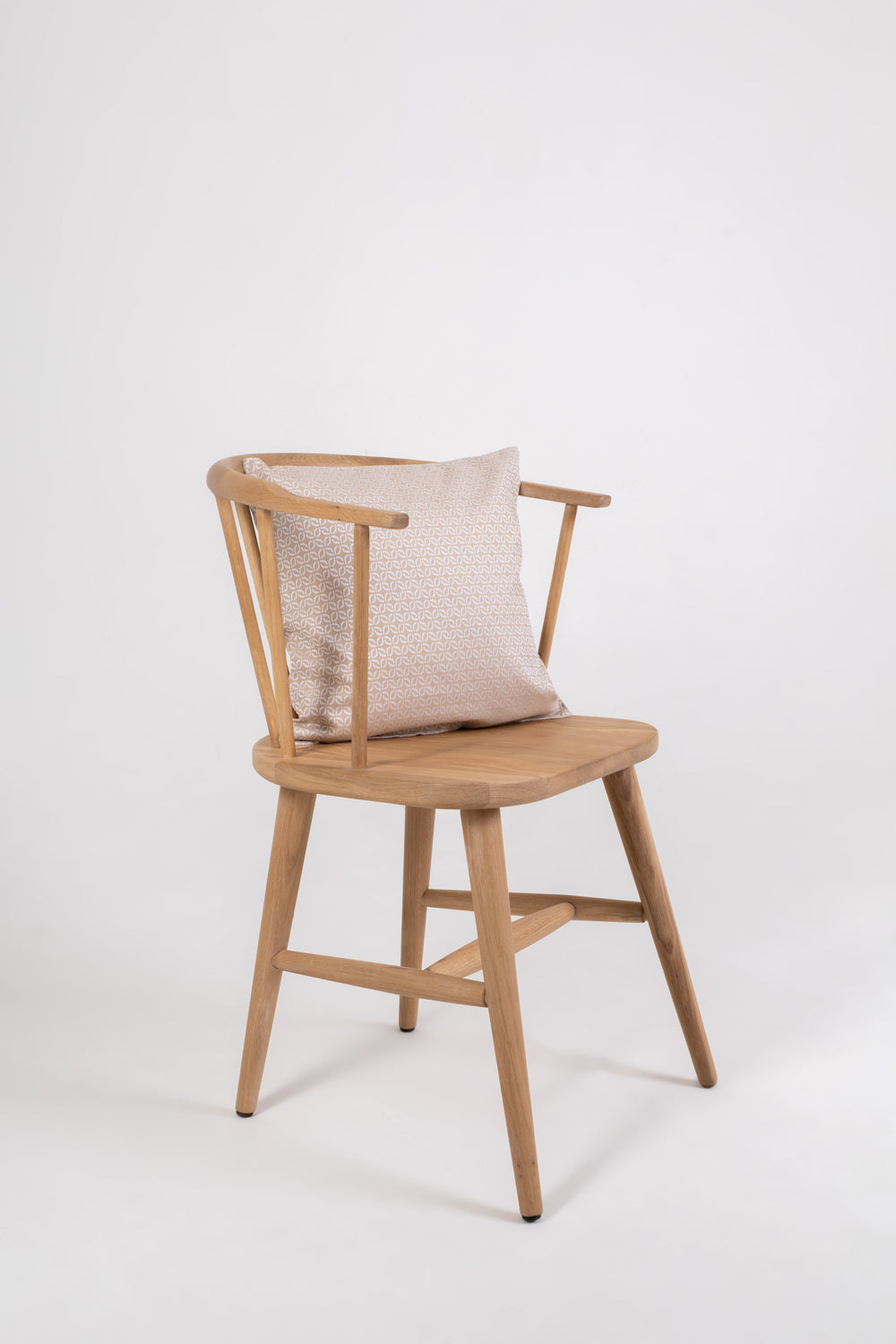 A beige cushion with a clover pattern on a wooden chair with no one sitting