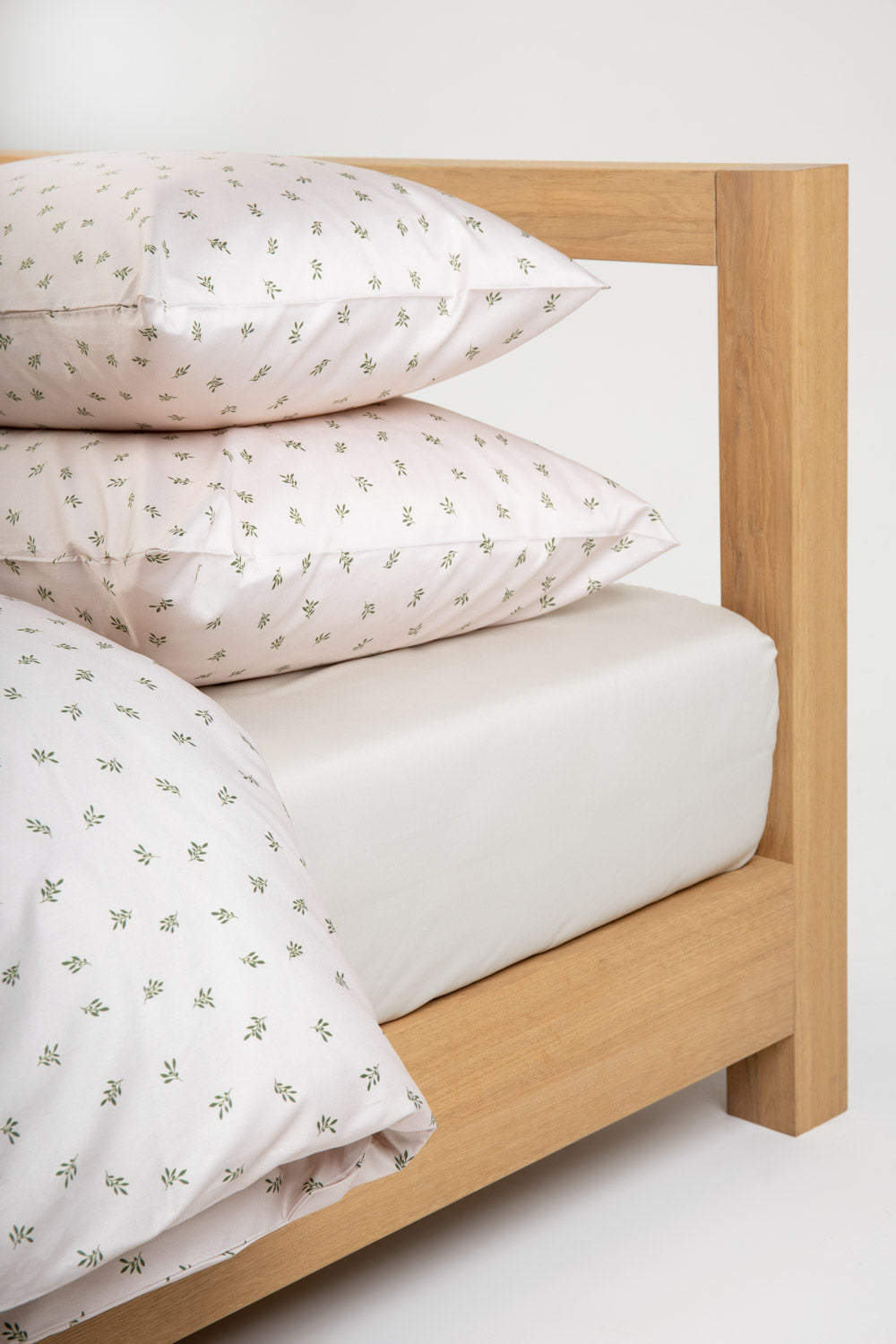 bige bedding with green olive pattern on a wooden bed