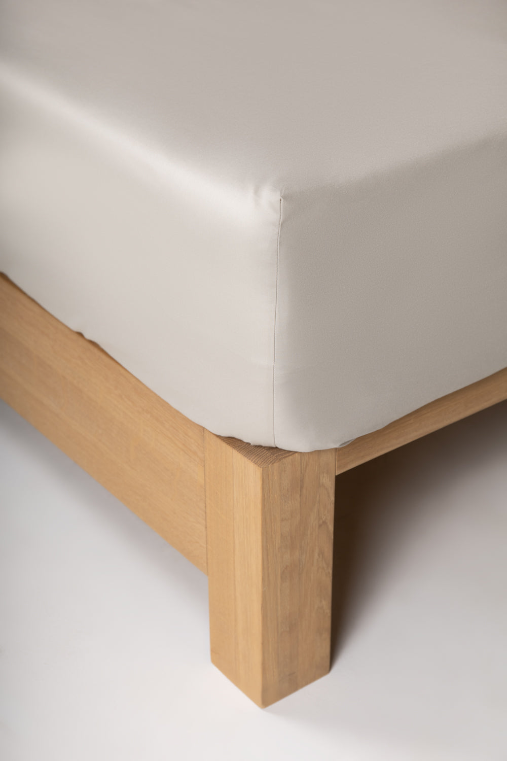 Corner of a beige cotton fitted sheet with a rubber strip on the corner, showcasing the high-quality fabric and breathability.