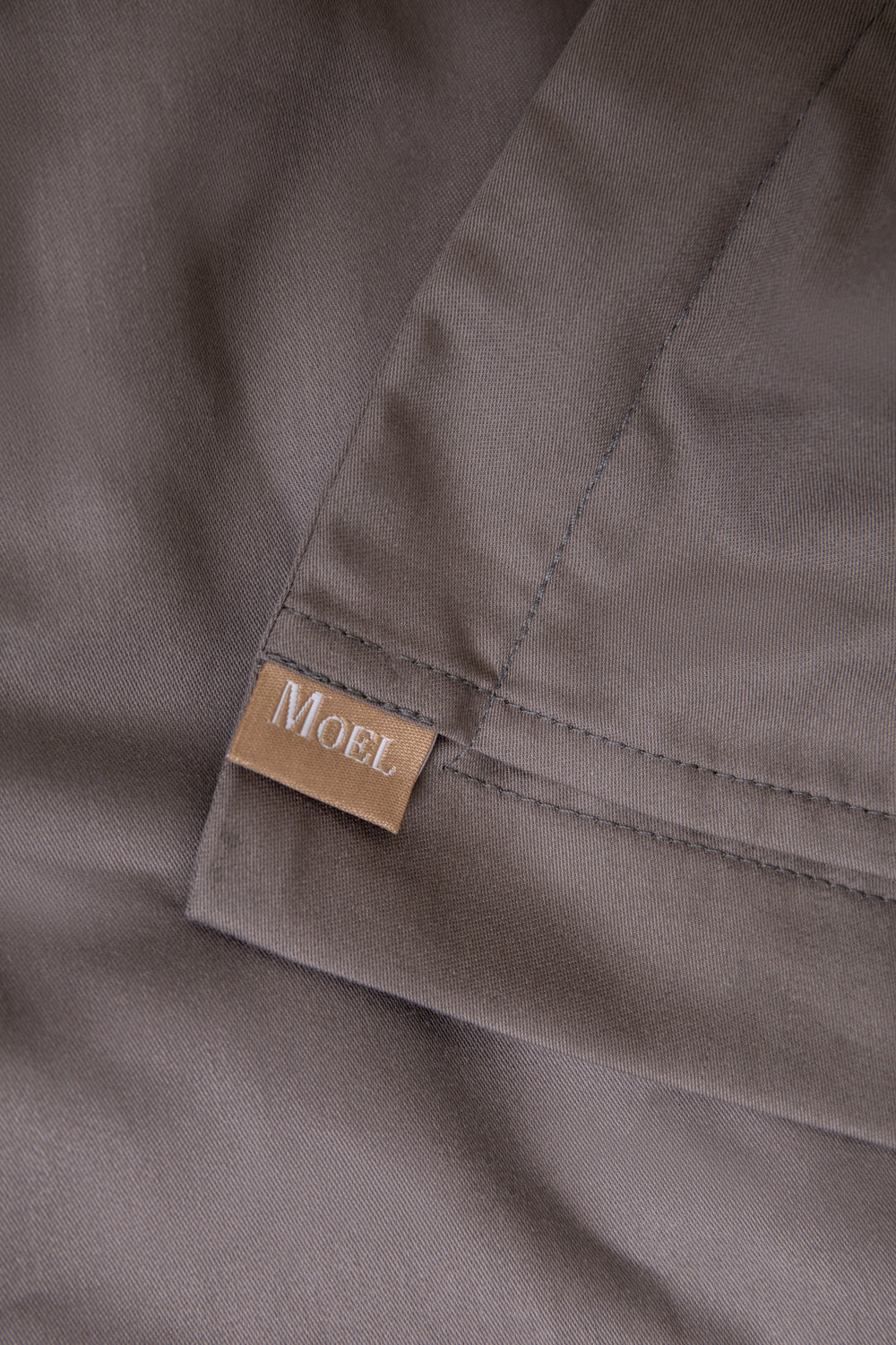 Close-up of a gray taupe fabric with a 'MOEL' label.