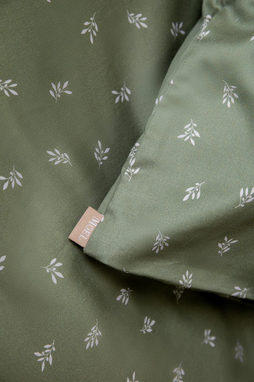 Green fabric with white floral pattern and a visible brand tag.