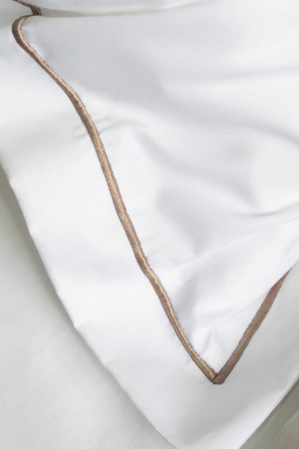 Close-up of a white pillow with beige piping 