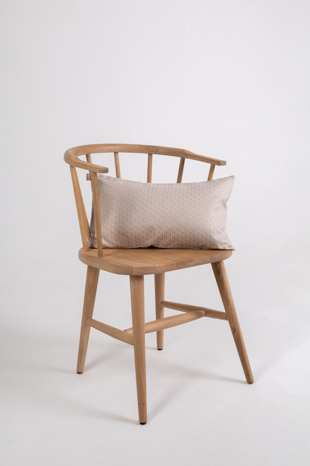 A beige cushion with a clover pattern on a wooden chair with no one sitting