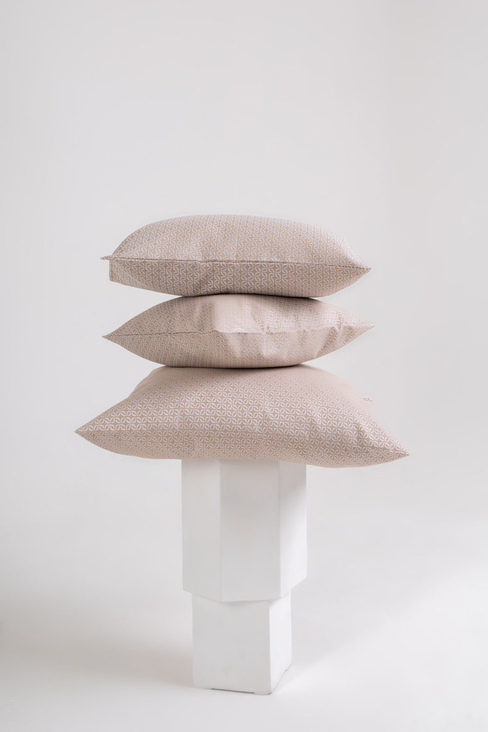 A beige cushion with a clover pattern on a wooden chair with no one sitting