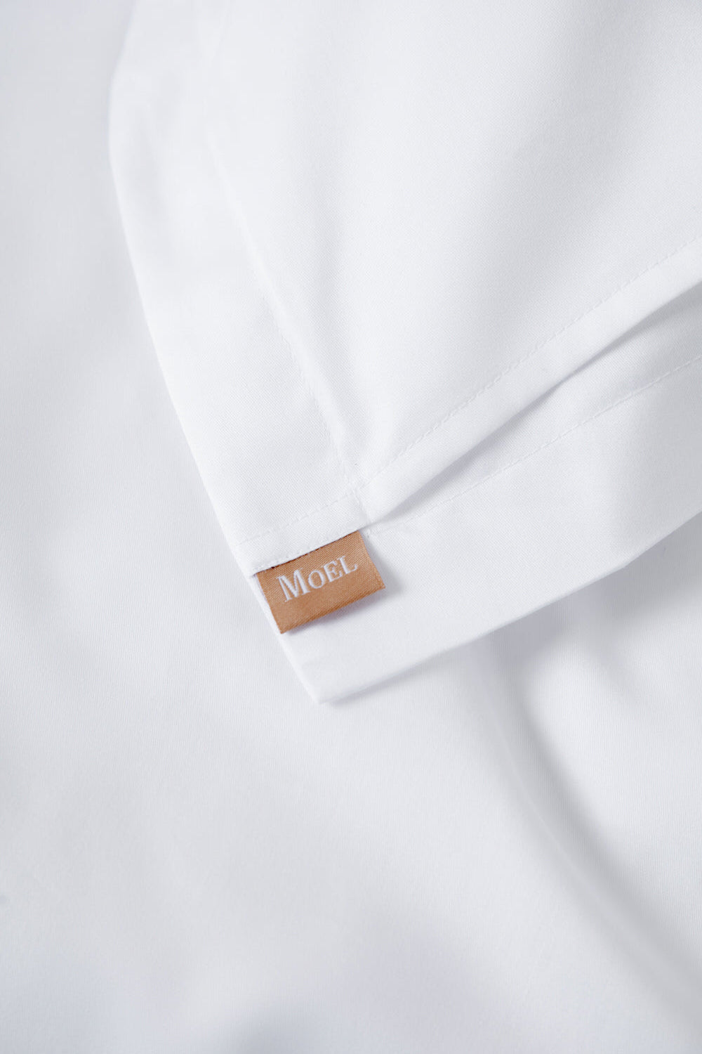 Close-up of a white bedding with a Moel label o
