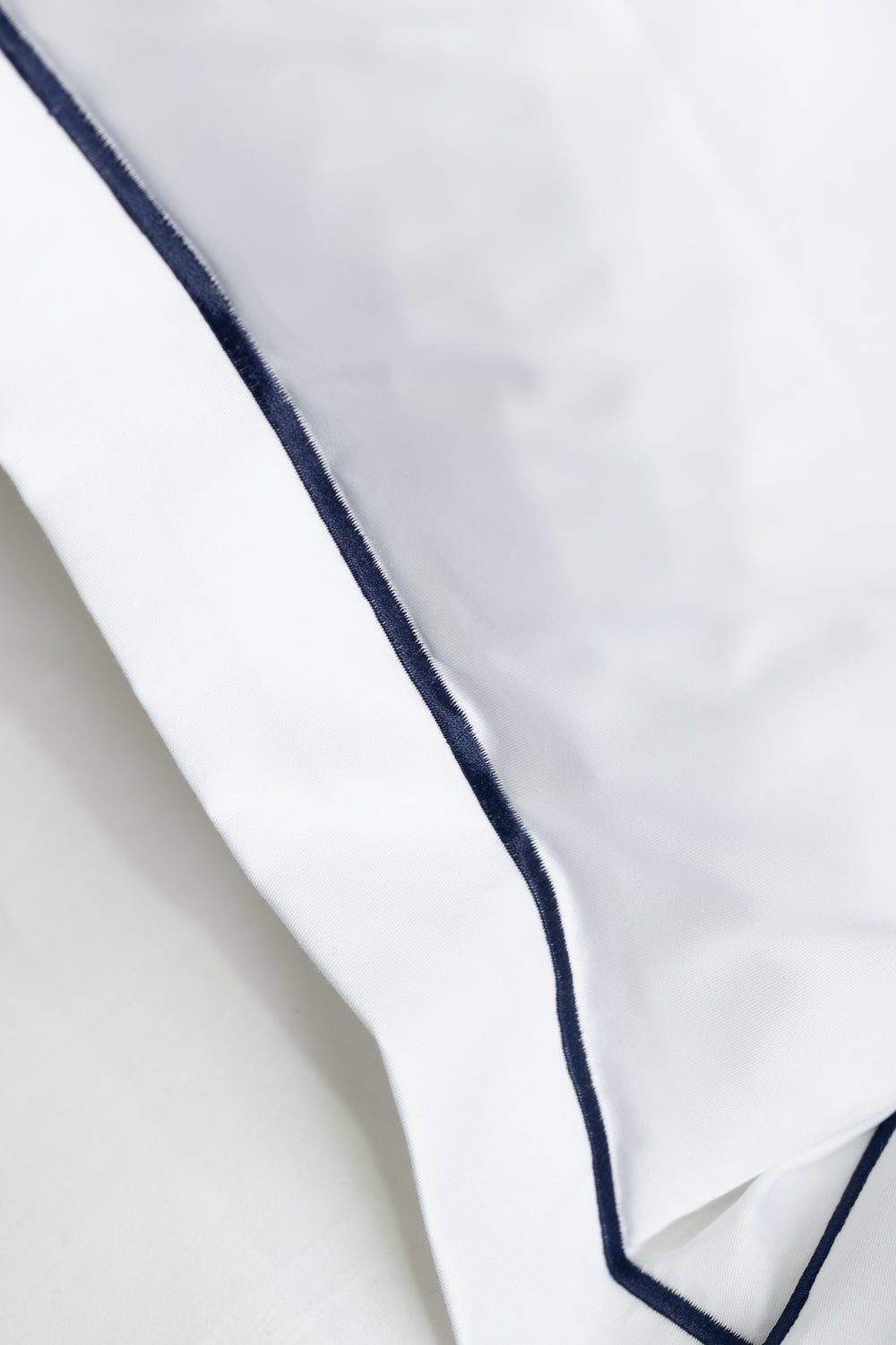 White pillow with navy blue piping 